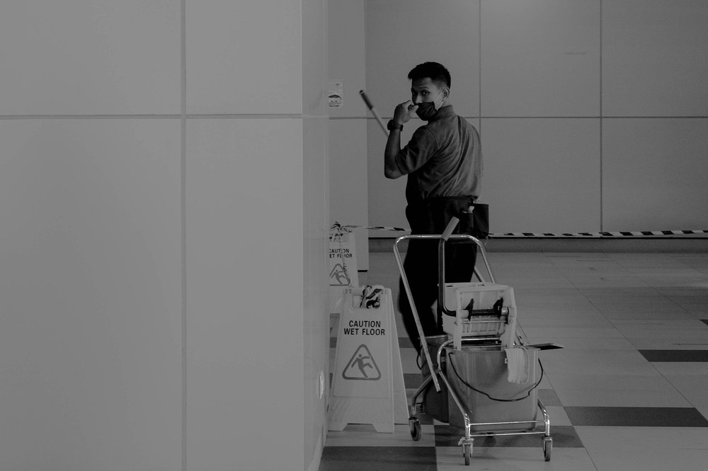 Janitor with a cleaning cart in a commercial hallway