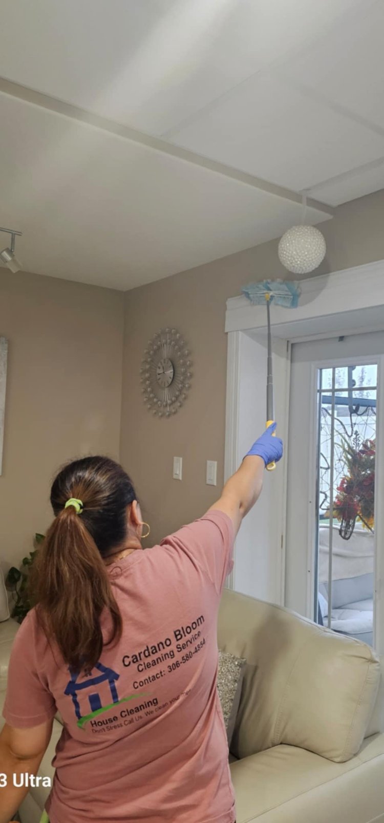 A Cardano Bloom team member dusting a ceiling light in a client's living room
